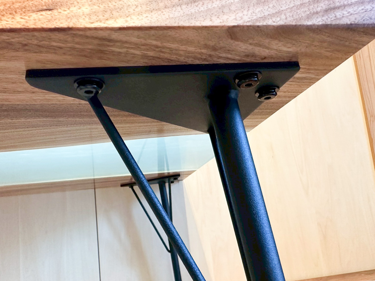 天然木テーブルの裏面にしっかりと固定された、マットな黒色のアイアン脚の接合部分