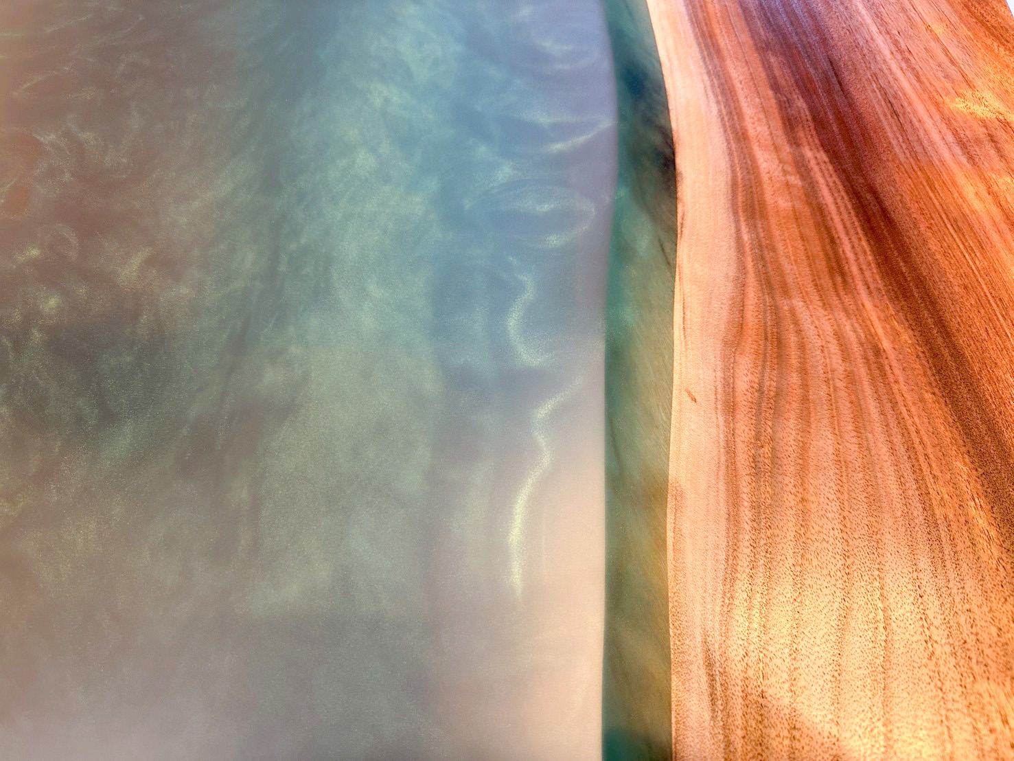 鮮やかな茶色の木材と、光の当たり方で表情を変えるパールな質感のグリーンのレジンを捉えた詳細写真