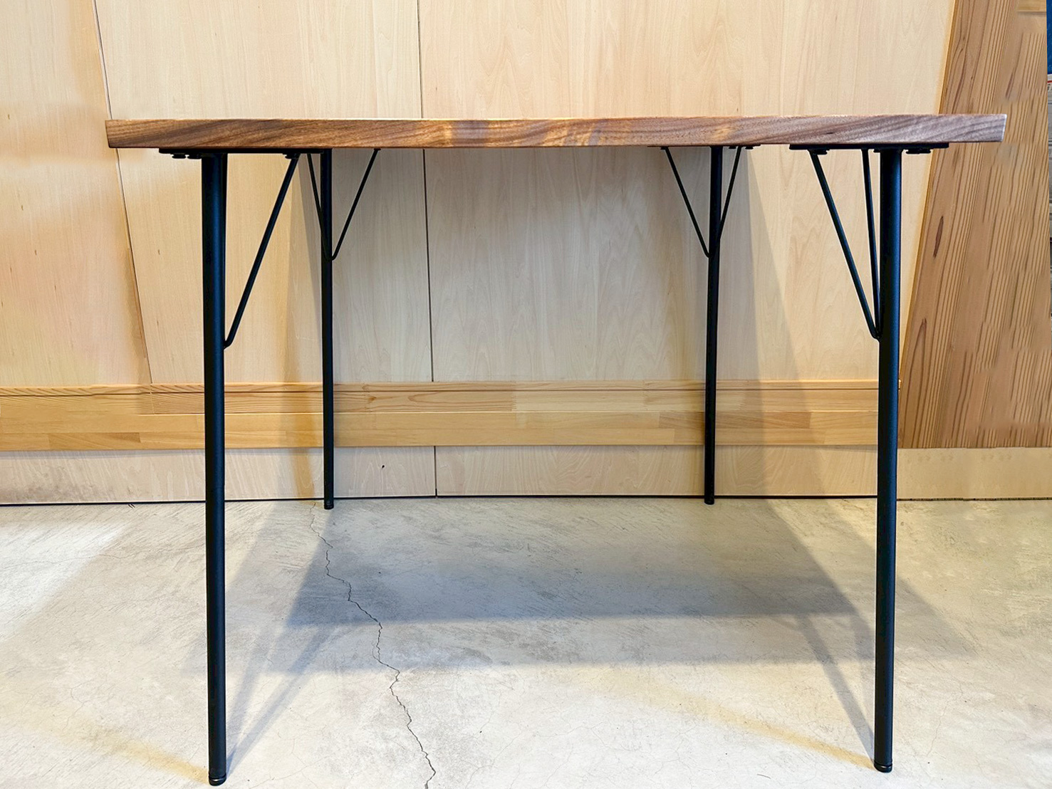 木の質感を活かした天板と、スリムな黒のアイアン脚が組み合わさったテーブルのサイドシルエット