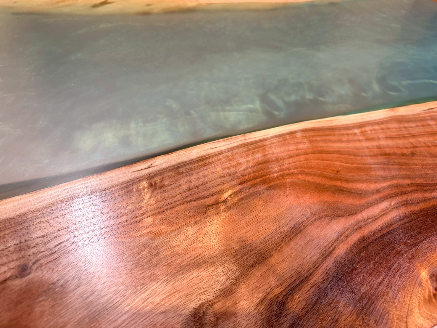 深い色味の木目と、透明感のあるスモーキーなエメラルドグリーンのレジンが隣り合う天板の表面